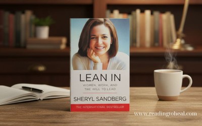 The cover of "Lean In" by Sheryl Sandberg placed on a wooden table next to a hot cup of coffee and a notebook in an office setting.