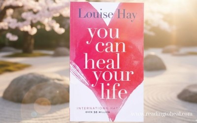 A person holding the yellow cover of "You Can Heal Your Life" by Louise L. Hay with a rainbow design, showing over 39 million copies sold.