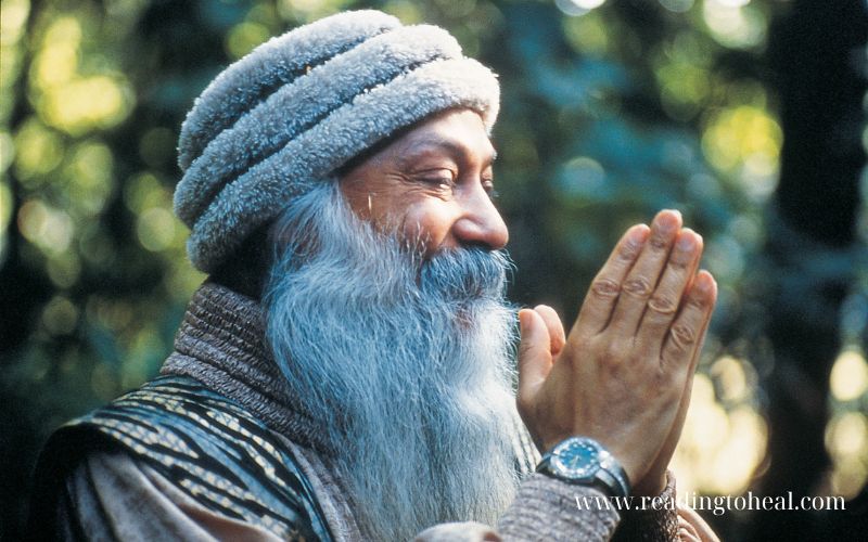 Close up of Osho with hands in prayer position and a blue watch